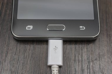 Hareket eden smartphones ahşap bir masa üzerinde beyaz bir tel şarj