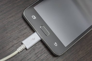 Hareket eden smartphones ahşap bir masa üzerinde beyaz bir tel şarj