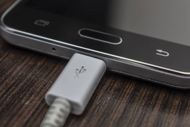 Hareket eden smartphones ahşap bir masa üzerinde beyaz bir tel şarj