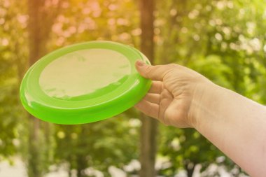 el ile a birden parlamak çerçevesinin bir yaz gününde parkta bir frizbi disk atma