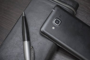 bir kalem ve çanta yalan bir ahşap masa arka plan üzerine telefonla