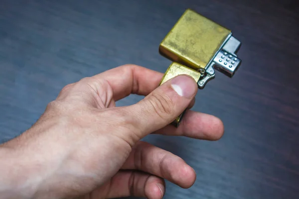 Handgehaltenes Goldenes Faltfeuerzeug Auf Dunklem Hintergrund Gelb Blauen Tönen Wärme — Stockfoto