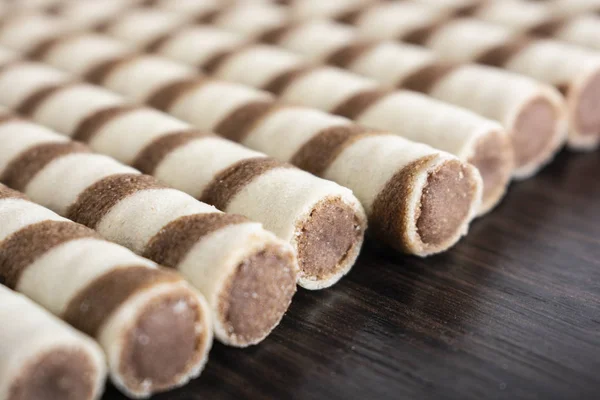 Striped waffle rolls filled with chocolate closeup background