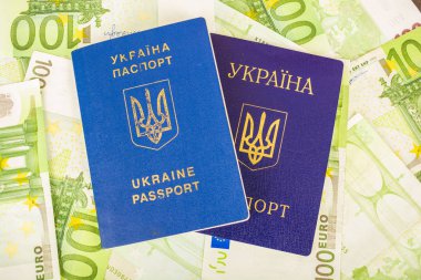 Bir ikinci sivil pasaport euro banknot 100 nominal değerinin içinde arka planı tarafından yaralı iki Ukraynalı pasaportlar