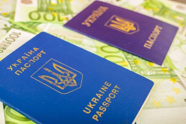 Bir ikinci sivil pasaport euro banknot 100 nominal değerinin içinde arka planı tarafından yaralı iki Ukraynalı pasaportlar