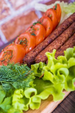 Lulya-kebap. Şiş kebap doldurma bir sopa. Geleneksel kafkas çanak. Bir kesme tahtası üzerinde yeşil salata, ketçap, baharat, domates bir tuğla duvar arka planda
