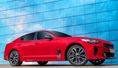 Kırmızı araba mavi gökyüzü arka plan beyaz bulutlar ile üzerinde. Bir avtomobil tasarım çözümleri için mobil bir şık, modern, parlak görüntü.