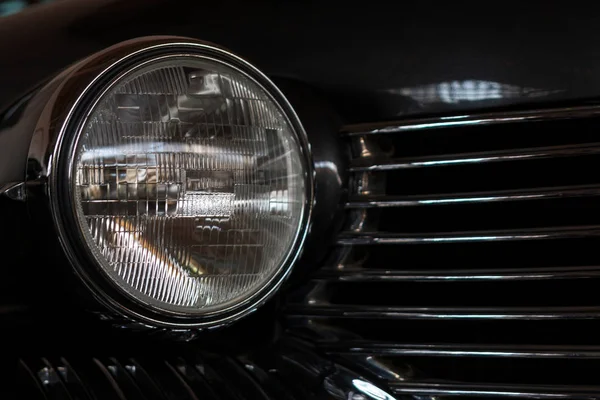 The headlight of an antique, rarity, vintage black car.