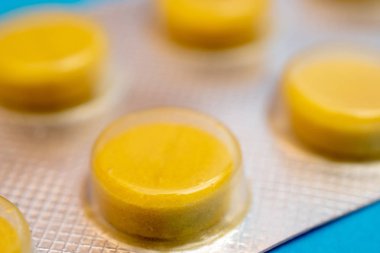 Bir paket içinde yuvarlak, sarı tabletler.