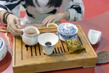 Çin çay töreni. Kız çaydanlığı ocağa çay fincan içine dökülen..