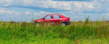 yeşil çim gökyüzü ile yolda kırmızı araba