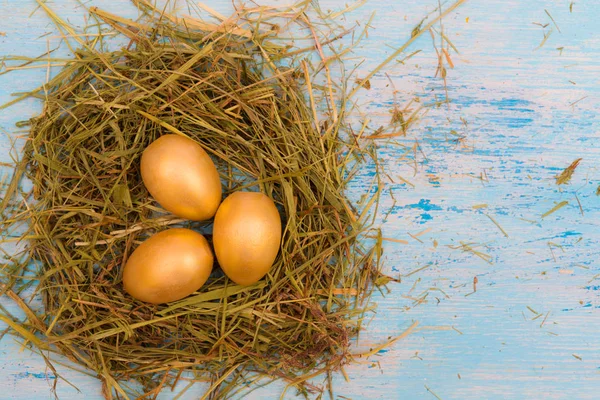 Huevos Pascua Dorados Nido Paja Sobre Fondo Azul —  Fotos de Stock