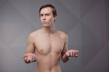 Gri arka planda çıplak gövdeli genç adamın gündelik stüdyo portresi