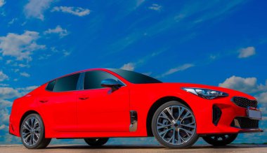 Beyaz bulutlarla mavi gökyüzü arka plan üzerinde kırmızı araba. Tasarım çözümleri için otomatik mobilin şık, modern, parlak görüntüsü.