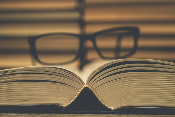 Kitapların arka planında gözlükler var. Bilginin, bilimin, çalışmanın, bilgeliğin sembolü.