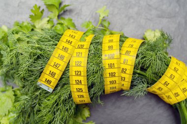 Çevreyi ölçmek için şerit çekiliyor. Diyet pişirmek için sebzeler