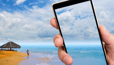 Akıllı telefon ekranında Sandy Ocean plajı. Tropiklerde güneşli bir gün.