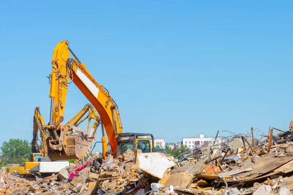 Eski binanın yıkımı. Harabelerin üzerindeki sarı kazıcı. Fotoğraf akıllı telefon. Akıllı telefon elindeydi. Ekranda kazıcı. 