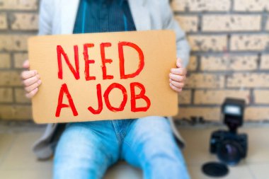 Fotoğrafçı işini kaybetti. Adamın elinde posteri var, işe ihtiyacı var. İşsizlik toplumsal bir sorundur.