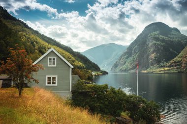 Typical Norwegian  house in the background of a picturesque fjord. Beautiful Norwegian landscape with a house and atmospheric sky. clipart