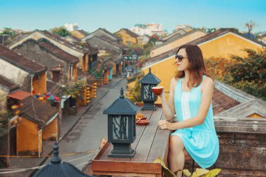 Turist kız Hoi An, Vietnam eski şehir bakan kahve içecekler. Genç bir kadın çatıdan eski Vietnam şehrinin en iyi manzarasının tadını çıkarıyor. Vietnam popüler bir turistik yer