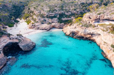Turistler, Menorca İspanya 'daki tenha Cala des Talaier plajının keyfini çıkarıyorlar..