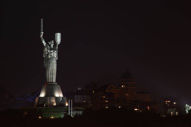 Zemin şehrin karşı güzel aydınlatılmış bir heykel ile gece manzarası