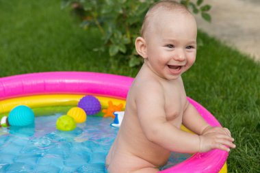 Küçük bir çocuk havuzda banyo yapıyor, yazın şişme çocukların şişme havuzunda.