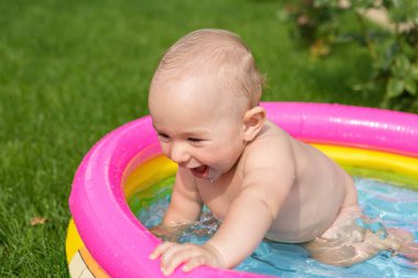 Küçük bir çocuk havuzda banyo yapıyor, yazın şişme çocukların şişme havuzunda.
