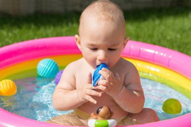 Küçük bir çocuk havuzda banyo yapıyor, yazın şişme çocukların şişme havuzunda.