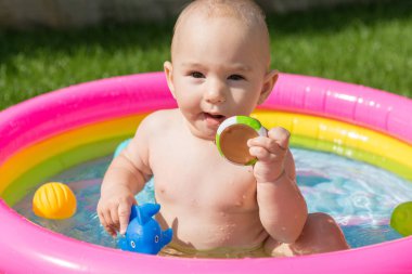 Küçük bir çocuk havuzda banyo yapıyor, yazın şişme çocukların şişme havuzunda.