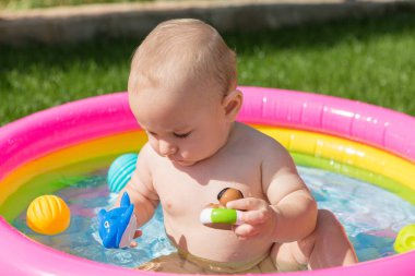 Küçük bir çocuk havuzda banyo yapıyor, yazın şişme çocukların şişme havuzunda.