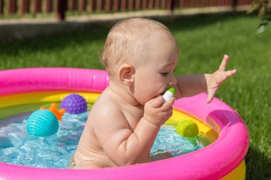 Küçük bir çocuk havuzda banyo yapıyor, yazın şişme çocukların şişme havuzunda.