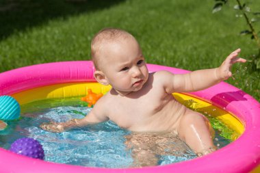 Küçük bir çocuk havuzda banyo yapıyor, yazın şişme çocukların şişme havuzunda.