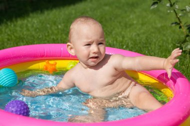 Küçük bir çocuk havuzda banyo yapıyor, yazın şişme çocukların şişme havuzunda.
