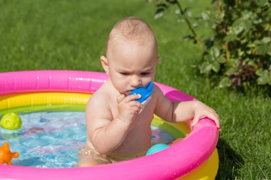 Küçük bir çocuk havuzda banyo yapıyor, yazın şişme çocukların şişme havuzunda.