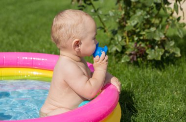 Küçük bir çocuk havuzda banyo yapıyor, yazın şişme çocukların şişme havuzunda.