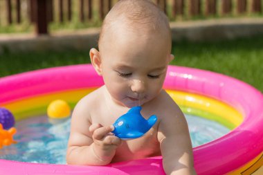 Küçük bir çocuk havuzda banyo yapıyor, yazın şişme çocukların şişme havuzunda.