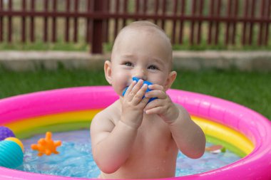 Küçük bir çocuk havuzda banyo yapıyor, yazın şişme çocukların şişme havuzunda.