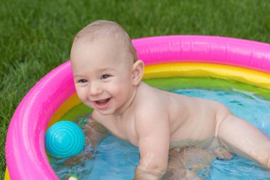 Küçük bir çocuk havuzda banyo yapıyor, yazın şişme çocukların şişme havuzunda.
