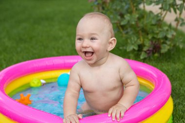 Küçük bir çocuk havuzda banyo yapıyor, yazın şişme çocukların şişme havuzunda.
