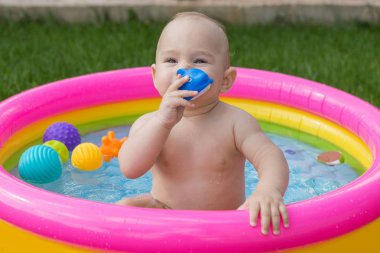 Küçük bir çocuk havuzda banyo yapıyor, yazın şişme çocukların şişme havuzunda.