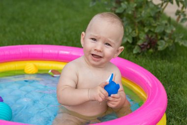 Küçük bir çocuk havuzda banyo yapıyor, yazın şişme çocukların şişme havuzunda.