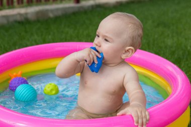 Küçük bir çocuk havuzda banyo yapıyor, yazın şişme çocukların şişme havuzunda.