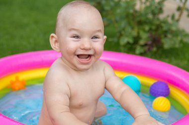 Küçük bir çocuk havuzda banyo yapıyor, yazın şişme çocukların şişme havuzunda.