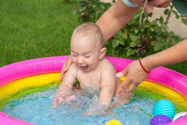 Küçük bir çocuk havuzda banyo yapıyor, yazın şişme çocukların şişme havuzunda.