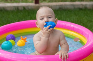 Küçük bir çocuk havuzda banyo yapıyor, yazın şişme çocukların şişme havuzunda.