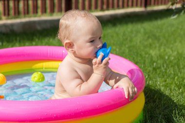 Küçük bir çocuk havuzda banyo yapıyor, yazın şişme çocukların şişme havuzunda.