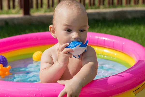 Küçük bir çocuk havuzda banyo yapıyor, yazın şişme çocukların şişme havuzunda.
