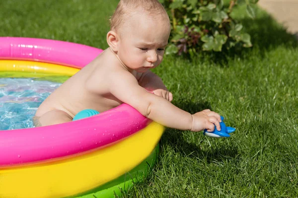 A small child is bathing in a pool, inflatable children\'s inflatable pool in summer